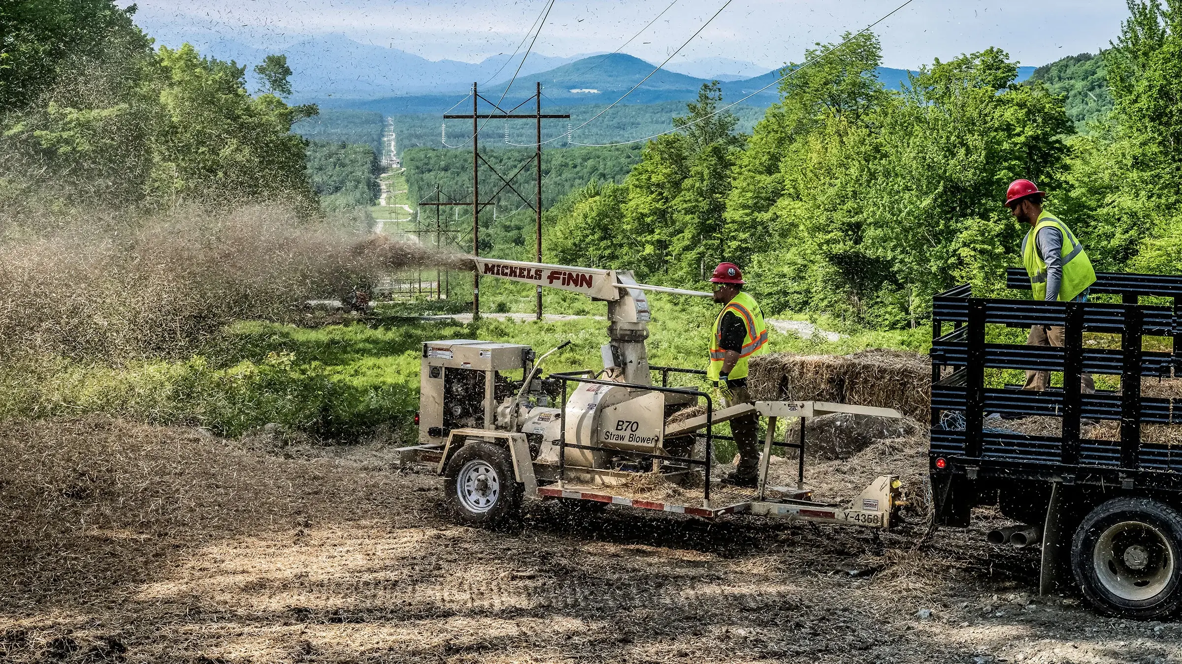 A person uses a machine to blow seed into place after a construction project was done