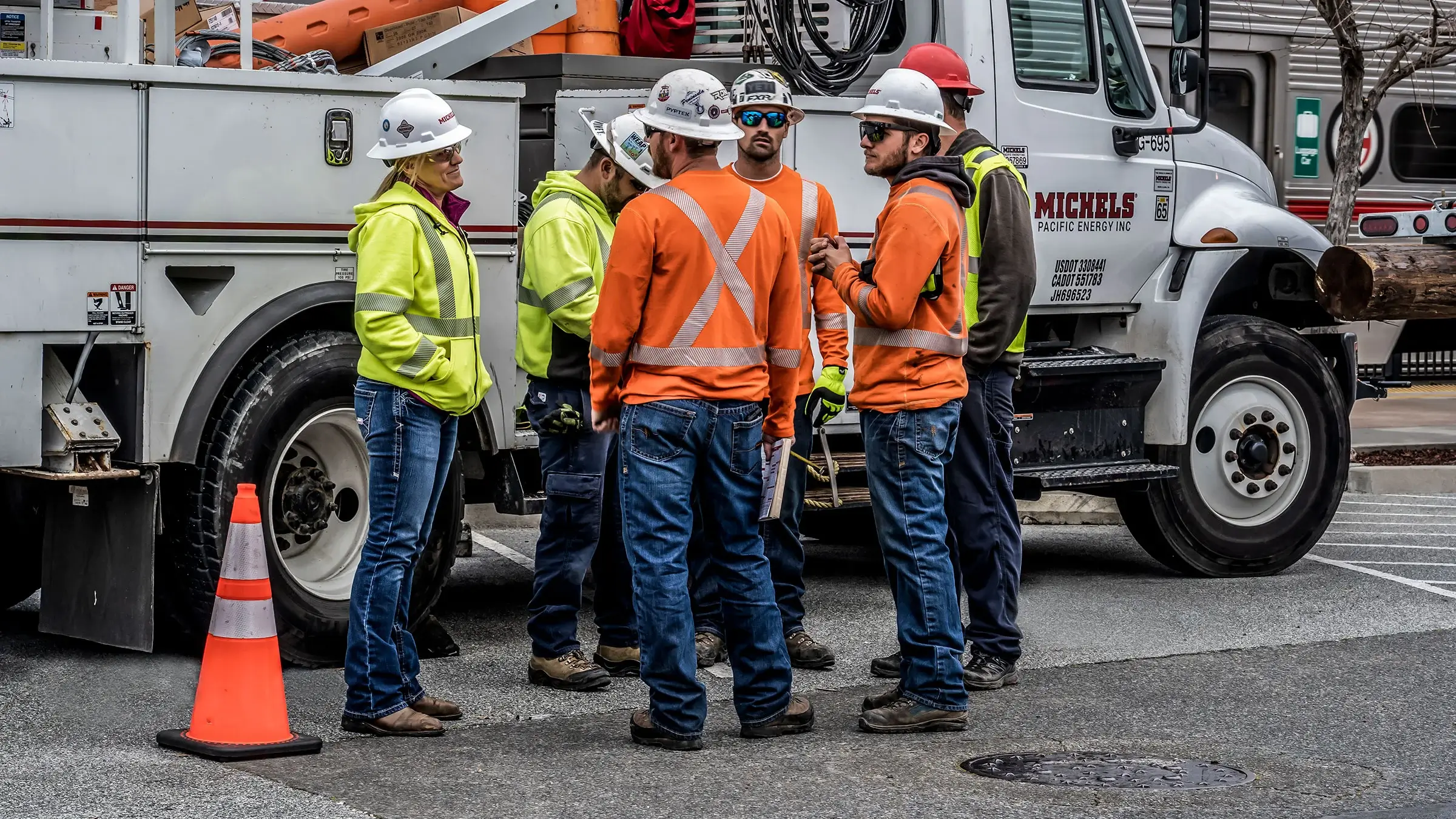 Group of workers standing in front of a bucket truck discussing a project.