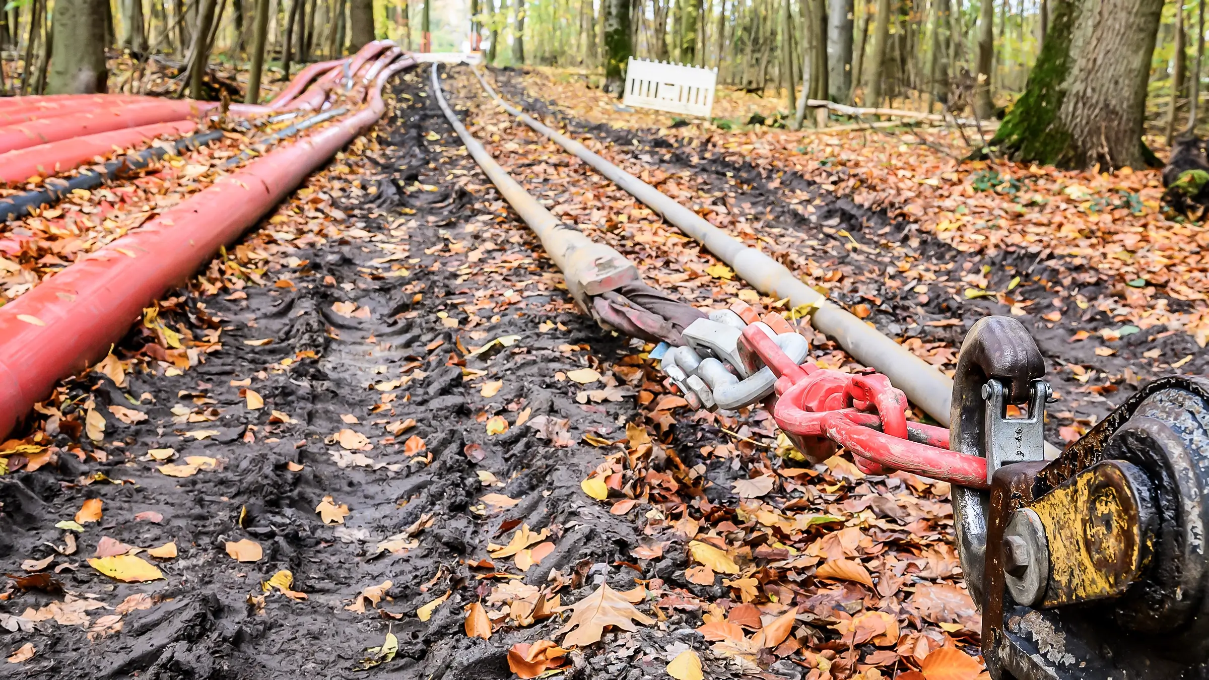 Pipes being pulled through rural wooded area.